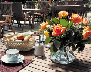 un tavolo con un vaso di fiori e una ciotola di pane di Zum Rebhang Bed & Breakfast a Oestrich-Winkel