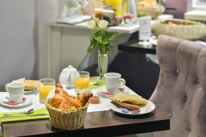 einen Frühstückstisch mit einem Korb mit Brot und Orangensaft in der Unterkunft Cristal Hôtel Restaurant - Logis Hotels in Saumur