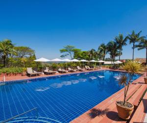 a large swimming pool with chairs and umbrellas at Hotel Villa Rossa in São Roque