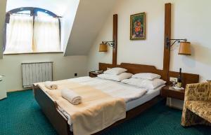 um quarto com uma cama grande e uma cadeira em Gasthof Laci Betyár em Hajdúszoboszló