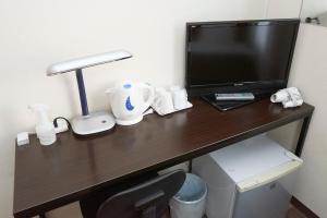 una scrivania con una televisione e una lampada di Hotel Select Inn Utsunomiya a Utsunomiya