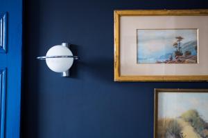 un mur bleu avec deux photos et une lumière sur celui-ci dans l'établissement B&B Villa 36, à Bruxelles