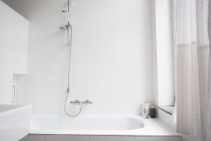 La salle de bains blanche est pourvue d'une douche et d'une baignoire. dans l'établissement B&B Villa 36, à Bruxelles