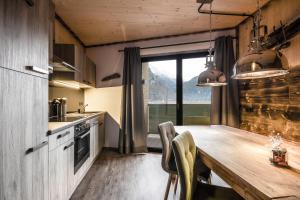 a kitchen with a wooden table and a large window at Apart Gamper in Längenfeld