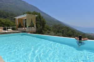 une personne dans une piscine avec une montagne en arrière-plan dans l'établissement Ölüdeniz Loft - Adults Only, à Ölüdeniz