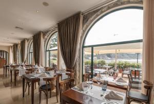 - un restaurant avec des tables, des chaises et de grandes fenêtres dans l'établissement Vila Gale Ericeira, à Ericeira