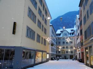 eine Stadtstraße mit Gebäuden im Schnee in der Unterkunft Central Hotel Post in Chur