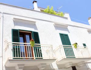 a white building with green shutters on a balcony at Dimora Dioniso in Polignano a Mare