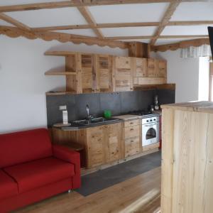 a kitchen with wooden cabinets and a red couch at Appartamento Mariastella in Andalo