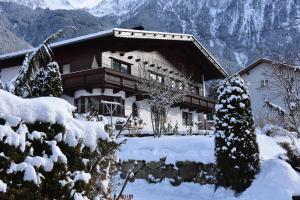 una casa ricoperta di neve di fronte a una montagna di Appartements Falkner Dorli a Oetz