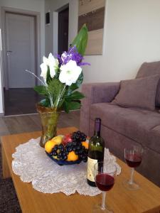 a table with a bowl of fruit and a bottle of wine at Apartment Milmari Sunny View G3 in Kopaonik