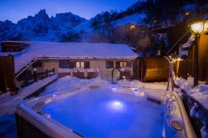 una vasca idromassaggio coperta di neve di fronte a una casa di Hotel Pilier D'Angle & Wellness a Courmayeur