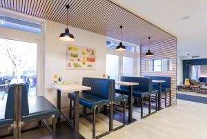 un restaurant avec des chaises bleues, des tables et des fenêtres dans l'établissement JUFA Hotel Graz City, à Graz