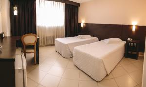 a hotel room with two beds and a table at Hotel Dunamys Curitiba in Curitiba