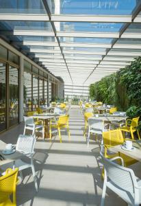 eine Cafeteria mit Tischen, Stühlen und gelben Stühlen in der Unterkunft Hotel El Dorado Bogota in Bogotá