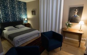 a bedroom with a bed and a blue chair at La Tillaie SPA et Sauna in Pont-lʼAbbé-dʼArnoult