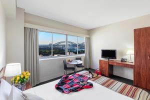 Cette chambre comprend un lit, un bureau et une fenêtre. dans l'établissement Macleay Hotel, à Sydney