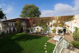 una casa con un patio con sillas y mesas en La Tillaie SPA et Sauna, en Pont-lʼAbbé-dʼArnoult