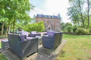 un grupo de sillas sentadas en un parque con un edificio en Logis Hôtel & Restaurant - Le Manoir de Sauvegrain, en Saint-Lambert