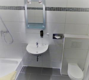 bagno con lavandino, servizi igienici e specchio di Hotel Dümptener Hof a Mülheim an der Ruhr