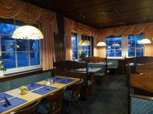 un ristorante con tavoli, sedie e finestre di Hotel Dümptener Hof a Mülheim an der Ruhr