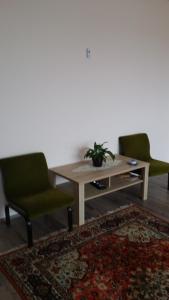 a living room with a table and two green chairs at Maros Vendégház in Mórahalom