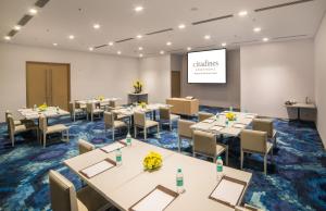 a conference room with tables and chairs and a screen at Citadines OMR Chennai in Chennai