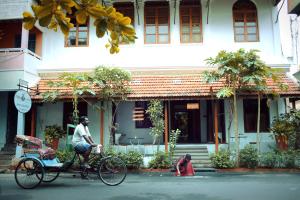 um homem a andar de bicicleta em frente a um edifício com um cão em Maison Perumal Pondicherry - a CGH Earth Experience em Pondicherry