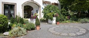 uma casa com um jardim com flores e um pátio em Hotel zur Mühle em Ismaning