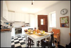 a kitchen with a table and a clock on the wall at Casa do Joaquim da Praia in Nazaré