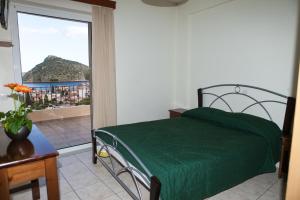 1 dormitorio con cama verde y balcón en Iliana Apartments, en Tolo