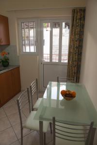 una cocina con mesa con sillas y un tazón de naranjas. en Iliana Apartments, en Tolo