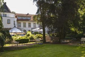 una casa con sedie e un prato di fronte ad essa di Hofgut Dippelshof Hotel- und Restaurant KG a Darmstadt