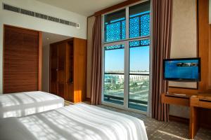 - une chambre avec un lit, une télévision et une grande fenêtre dans l'établissement Yas Island Rotana Abu Dhabi, à Abu Dhabi