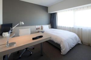 een slaapkamer met een bed en een bureau met een lamp bij X wave Funabashi in Funabashi