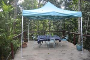 een tafel en stoelen onder een blauwe paraplu op een terras bij Tropical Bliss bed and breakfast in Mena Creek