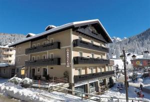 ein großes Gebäude mit Schnee auf dem Boden in der Unterkunft Hotel Garni Arnica ***S in Madonna di Campiglio