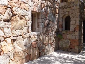 ein Steingebäude mit einem Fenster und einer Steinmauer in der Unterkunft Les chambres de l'Hôte Antique in Porto-Vecchio