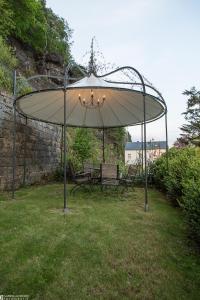 un grand parapluie dans une cour avec deux bancs dans l'établissement Albergo-Toscana, à Bad Schandau