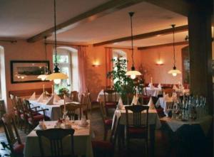 un restaurante con mesas y sillas con manteles blancos en Landhaus Heidehof, en Dippoldiswalde