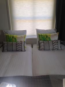 a white bed with two pillows and a window at The Riverside Logies & Restaurant in Maarssen