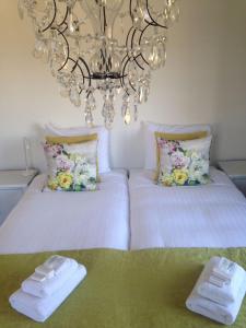 a bedroom with two beds with white sheets and a chandelier at The Riverside Logies & Restaurant in Maarssen