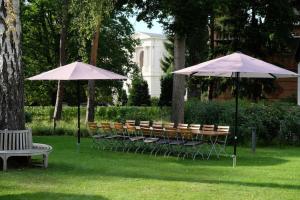 een groep stoelen en tafels met parasols in een park bij Forsthaus Sommerswalde in Sommerswalde