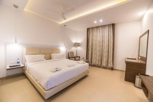 Un dormitorio con una gran cama blanca y una ventana en Hotel Vivera Grande, en Dindigul