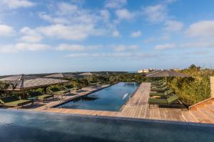 een zwembad met stoelen en parasols en de oceaan bij Hôtel & Spa Version Maquis Citadelle in Bonifacio