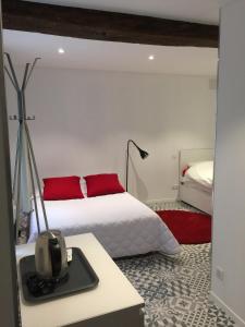 a bedroom with a white bed with red pillows at Hôtel Le Chambellan in Dijon