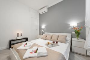 Trevi Apartment في روما: غرفة نوم بيضاء مع سرير عليه مناشف وحذاء