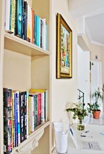 a book shelf filled with books next to a desk at Hotel Aegina in Aegina Town