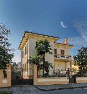 a house with a fence and a palm tree in front of it at Il Giardino Del Pettirosso in Lucca