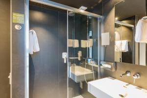 bagno con doccia, lavandino e specchio di ibis Styles Basel City a Basilea